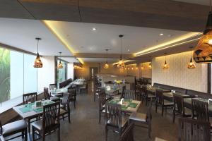 un restaurante con mesas de madera, sillas y luces en Samanvay Boutique Hotel, en Udupi