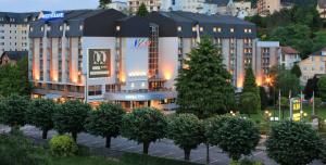 un hôtel avec beaucoup d'arbres devant lui dans l'établissement Hôtel Le Méditerranée, à Lourdes