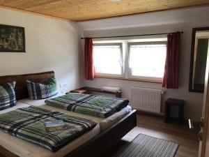 a bedroom with two beds and two windows at Pension Hofeck in Bernau im Schwarzwald
