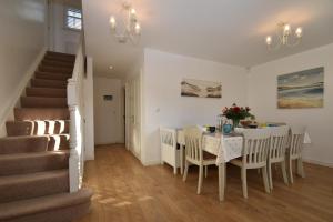 een eetkamer met een tafel en stoelen en een trap bij Strand House in Camber