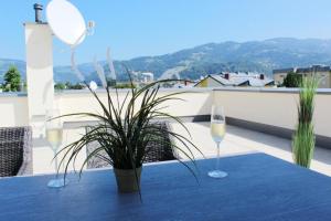 Dachterrassen Appartement Monte Lupo في فولفسبورغ: طاولة مع كأسين من النبيذ ونبات الفخار