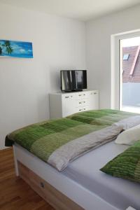 a white bedroom with a bed with a tv on it at Dachterrassen Appartement Monte Lupo in Wolfsberg