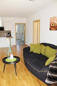 Dachterrassen Appartement Monte Lupo في فولفسبورغ: غرفة معيشة مع أريكة سوداء وطاولة