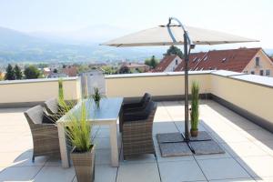 een tafel en stoelen op een balkon met een parasol bij Dachterrassen Appartement Monte Lupo in Wolfsberg