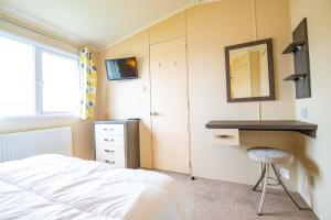 a bedroom with a bed and a desk and a mirror at Big Skies Platinum Plus Holiday Home with Wifi, Netflix, Dishwasher, Decking in Camber