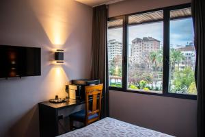 a hotel room with a bed and a desk and a window at Hotel Condestable Iranzo in Jaén