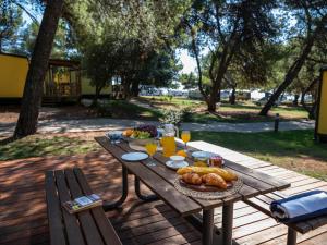 una mesa de picnic con comida y bebidas. en Mobile Homes Camp Pineta - Adriatic Kampovi en Fažana