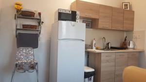 einen weißen Kühlschrank in einer Küche mit Holzschränken in der Unterkunft Kovács Vendégház in Mátraderecske