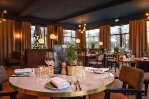 a dining room with a table and chairs and windows at De Zwaan Delden in Delden