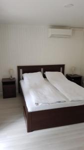 1 Schlafzimmer mit einem Bett mit weißer Bettwäsche und 2 Tischen in der Unterkunft Vila Goda & Vila Roma in Neringa