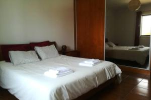 a bedroom with a large white bed with a mirror at Casa Mareco in Vila Nova de Milfontes