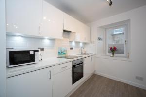 a white kitchen with a sink and a microwave at Seaesta Apartments in Macduff