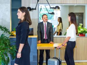 a man and two women standing at a desk in an office at Mercure Castres L'Occitan in Castres