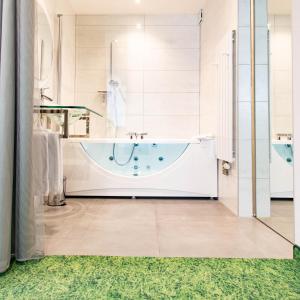 a bathroom with a tub and a green rug at Hotel Beaucour in Strasbourg