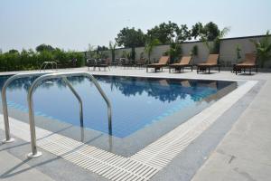 a swimming pool with benches and chairs next to a building at TreeHouse Morina, Vithalapur in Vithalpur