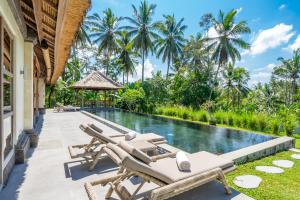 an infinity pool with chaise lounge chairs next to a villa at Rouge - Private Villa Jae in Ubud