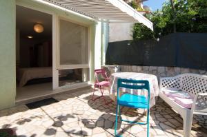 eine Terrasse mit Stühlen, einem Tisch und einem Sonnenschirm in der Unterkunft Apartments Lilly in Banjole