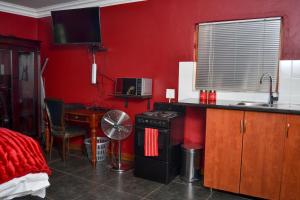 - une cuisine aux murs rouges et une table avec une cuisinière dans l'établissement Casa de Ross, à Pretoria