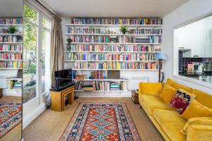 a living room with a yellow couch and bookshelves at ALTIDO Sunny 1-bed flat with terrace in Bayswater, near Paddington in London