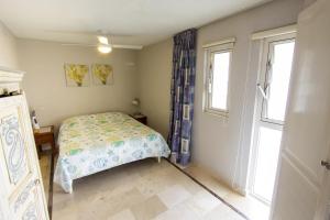 1 dormitorio pequeño con 1 cama y 2 ventanas en Seaside Apartment Seastar, en Kralendijk