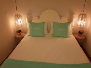 a bedroom with a white bed with two green pillows at Ferienwohnung MOMENTE in Waldbreitbach
