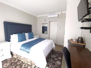 1 dormitorio con 1 cama blanca grande con almohadas azules en Lucolo Palace B&B - East London, en East London