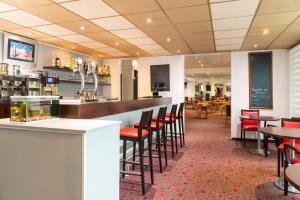 a restaurant with a bar with chairs and tables at ibis Longwy Mexy in Mexy