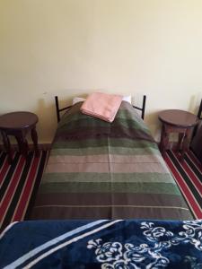 a bed in a room with two tables at Auberge Restaurant Les Coquelicots in Aït Tamellil