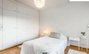 a white bedroom with a bed and white cabinets at Scandinavian design heart City Center Runeberginkatu in Helsinki