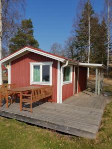 a red cabin with a wooden deck and a table at Askeviks Camping & Stugor in Sjötorp