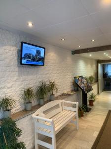 a waiting room with a bench and a tv on a wall at Hotel Mondial Comfort - Frankfurt City Centre in Frankfurt/Main