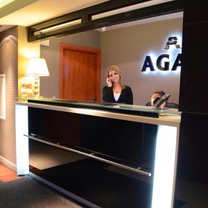 a woman talking on a cell phone at a reception desk at Agat Hotel in Łódź