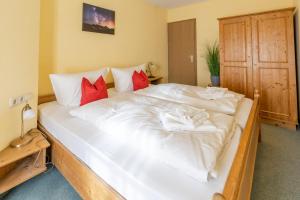 a large white bed in a room with red pillows at Ferienwohnung Auszeit in Bad Hindelang +6 photos