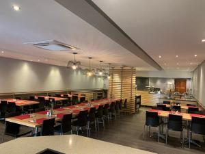 a restaurant with tables and chairs and a kitchen at Royal Hotel in Polokwane