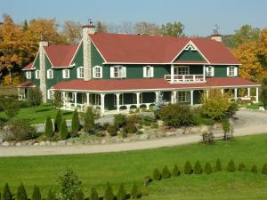 une grande maison verte avec un toit rouge dans l'établissement Le Baluchon Éco-villégiature, à Saint-Paulin