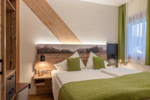a bedroom with a bed with a green comforter at Hotel Samerhof - Badestrand inklusive in Tröpolach