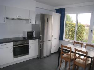 a kitchen with a stainless steel refrigerator and a table with chairs at Condor 19 in Nieuwpoort