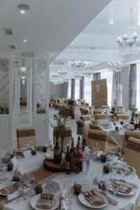een eetkamer met witte tafels en stoelen en kroonluchters bij Congress Hotel Verhovina in Kiev