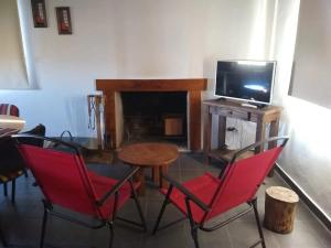 sala de estar con mesa, sillas y TV en Cabañas Otium en Uspallata