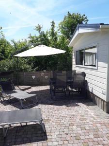 a patio with a table and chairs and an umbrella at Chalets van Minicamping De Braamhof in Koudekerke