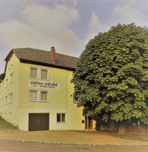 a large tree next to a yellow building at Gästehaus Goldhorn in Rödental