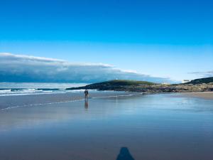 a person standing on a beach near the ocean at The Quies in Newquay