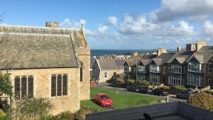 a red car parked in front of a group of houses at The Quies in Newquay