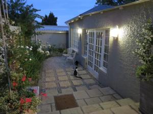 a cat sitting on a patio in front of a house at AppleBee Guest Cottages in Grahamstown