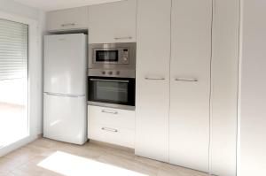a white kitchen with a refrigerator and a microwave at Vistamar 1 in Oliva