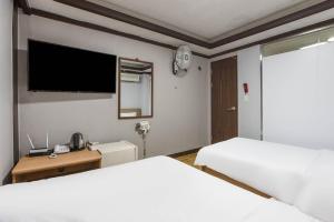 a bedroom with two beds and a flat screen tv at Keumkang Motel in Seoul