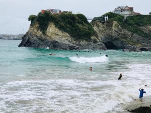 een groep mensen in het water op het strand bij The Quies in Newquay