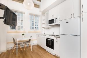 uma cozinha com electrodomésticos brancos e uma mesa com cadeiras em Les Lofts de Buade - Par Les Lofts Vieux-Québec em Cidade de Quebec