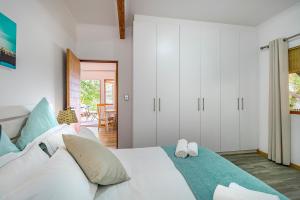 a bedroom with a white bed and white cabinets at Mountain View Cabana in Kommetjie