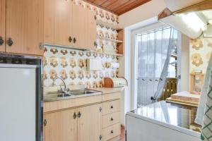 eine Küche mit Holzschränken, einem Waschbecken und einem Fenster in der Unterkunft Ciasa Christina - Attic in Moena